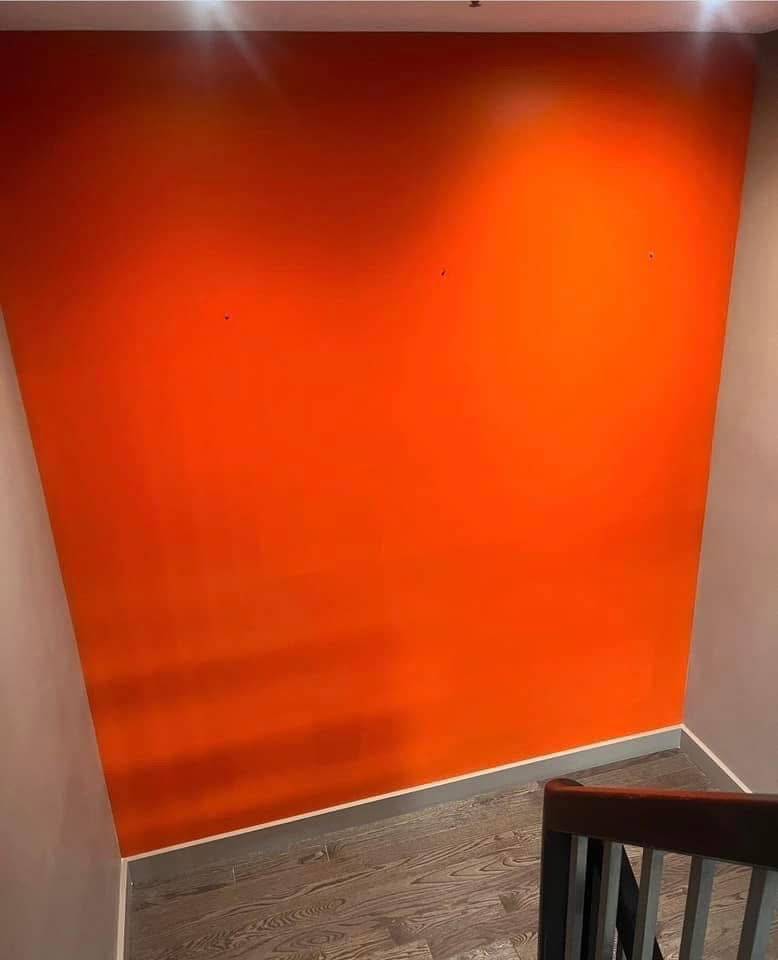 Burnt-orange accent wall with clean cut lines against a light ceiling and baseboard — Calgary accent wall painting by Timeless Interiors Ltd