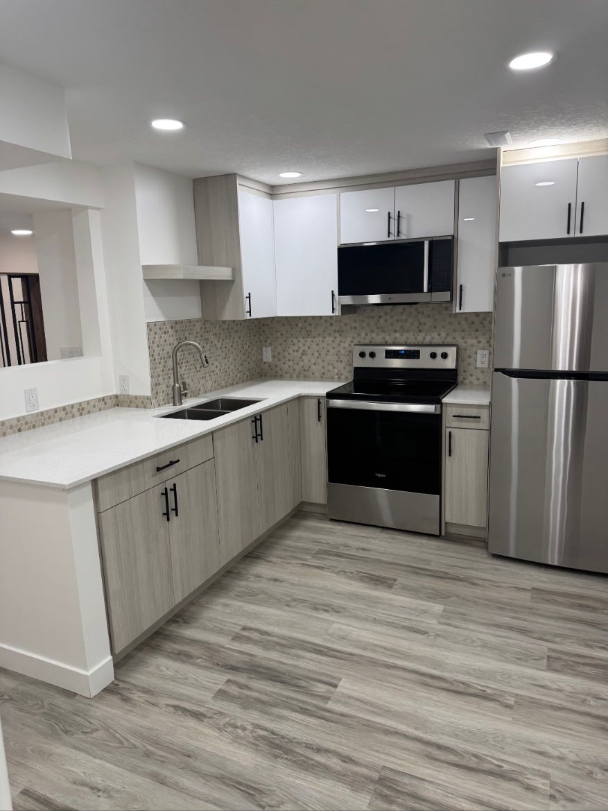 Calgary basement secondary suite kitchen with quartz countertops and full-size appliances by Timeless Interiors Ltd