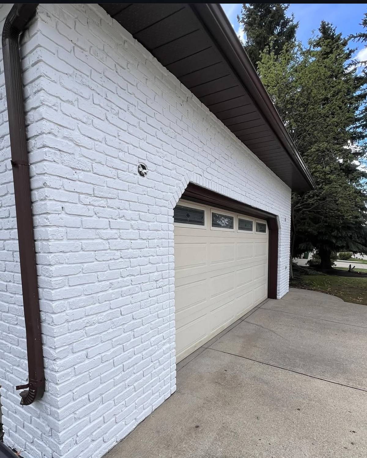 Same detached garage after brick painting in white with dark trim and fascia — Calgary exterior brick painting by Timeless Interiors Ltd