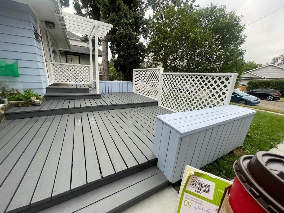 Completed Calgary deck painting in two-tone grey with white lattice privacy screen and repainted storage bench — Timeless Interiors Ltd
