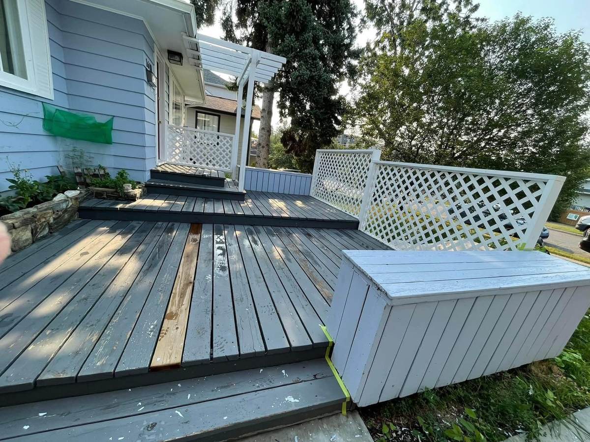 Front deck mid-refinish with bare replacement boards and worn grey stain — Calgary deck painting prep by Timeless Interiors Ltd