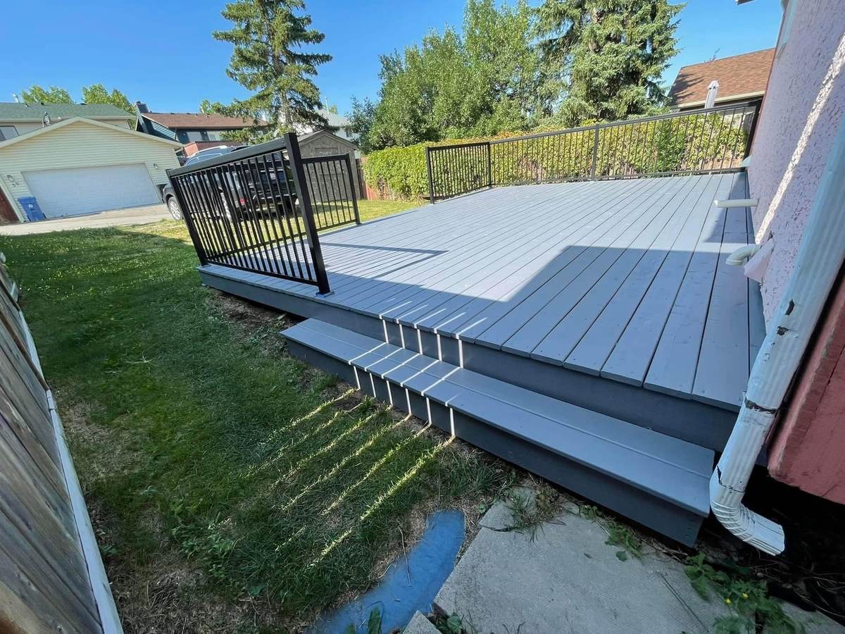 Same Calgary deck after refinishing, light grey deck boards with charcoal fascia and stair risers — deck staining by Timeless Interiors Ltd