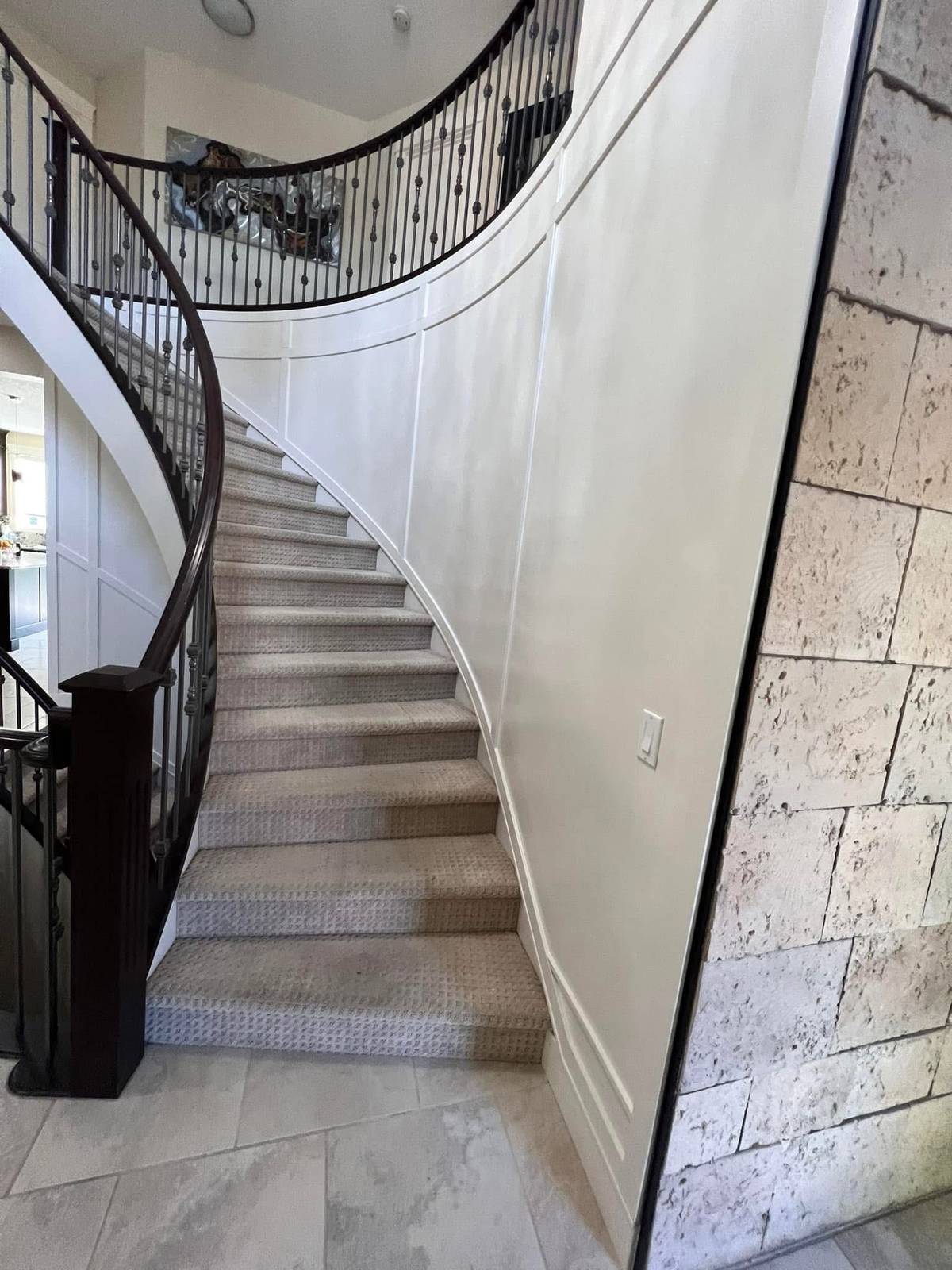 Curved staircase repainted in off-white with panel moulding picked out in the same tone — Calgary interior painting by Timeless Interiors Ltd