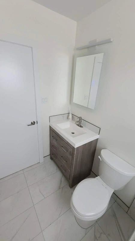 Calgary powder room renovation with wood-grain floating vanity and marble-look porcelain tile floor by Timeless Interiors Ltd